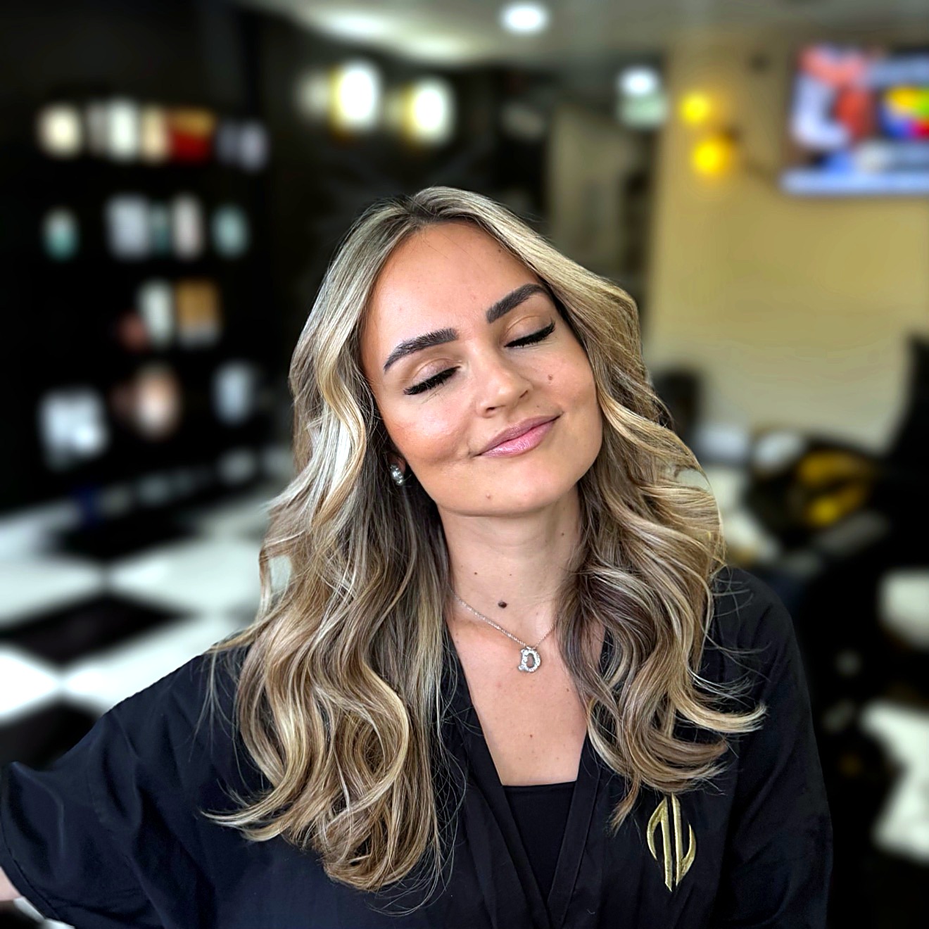 Smiling blonde woman with wavy hair in a salon cape